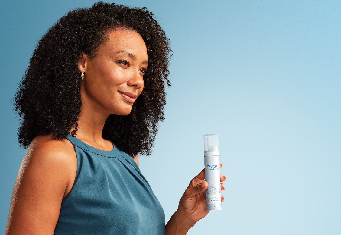 Woman smiling holding ZORYVE topical foam canister 