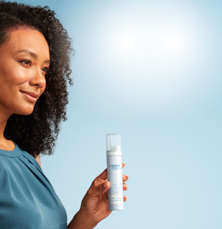 Woman smiling holding ZORYVE topical foam canister 